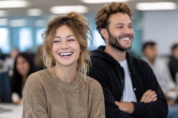 Enthusiastic young woman and smiling young man in casual clothing enjoying positive interaction indoors with diverse group background