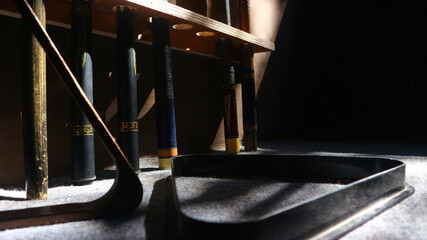 Billiard cues and rack illuminated by dramatic light, casting shadows and highlighting the texture...
