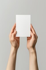 Faceless hands holding blank vertical business card on neutral white background, soft shadows, modern portrait branding style.