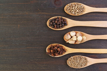 Assortment of Spices in Wooden Spoons on Black Wooden Background