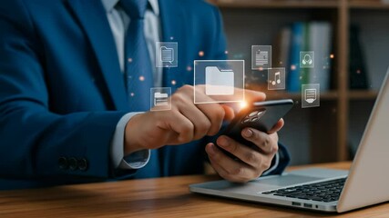 Business Data Management: A mature White businessman uses his smartphone to organize and access documents, data and music with a laptop on a desk indoors. - Powered by Adobe