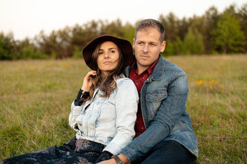 Young couple wearing denim jackets relaxing together in a meadow