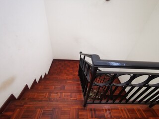 Indoor staircase with polished wooden steps and black iron railing, photographed from a diagonal...