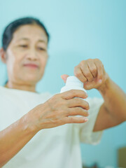 Senior Asian woman holding drugs for concept health care and medical. Healthy lifestyle people medicine bottle with pill for home care wellness health. Elderly care patient. Female reading drug labels