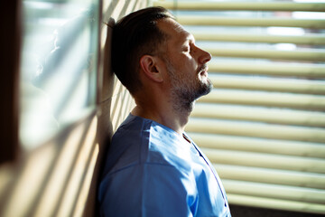 Exhausted healthcare worker resting against wall in hospital break room