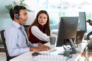 Obraz premium Two customer support professionals are working modern office. One is wearing headset and speaking, while other attentively listens. They are seated desks with computers, fostering collaborative