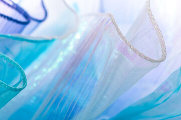 Close-up of translucent wavy fabric in blue and purple with shimmering texture &ndash; lightweight textile surface for fashion, elegance, design, and creative visual backgrounds with glowing light
