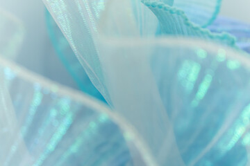 Close-up of layered light blue mesh fabric with shimmering, semi-transparent texture and delicate...