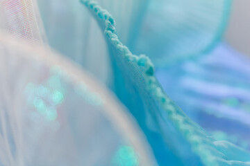 Close-up of shimmering light blue mesh fabric with soft folds and semi-transparent texture, ideal...
