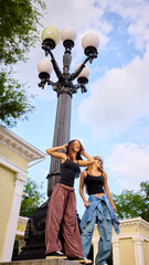 Youthful dancers pose next to an ornate street lamp under a blue sky. Concept of freedom and...