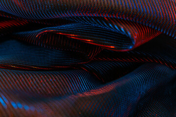 Luxurious close-up of draped, metallic-textured fabric with red and blue highlights, showcasing...