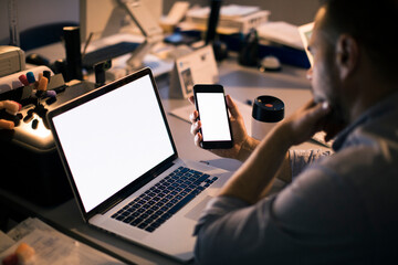 Man looking at blank phone screen at night in dark office workspace