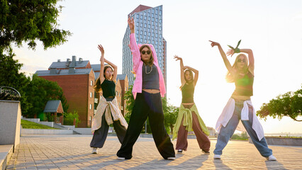 A group of diverse dancers performs an urban hip hop dance routine on a sunny city street. Concept...