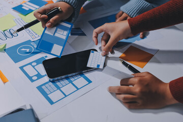 UX UI designer testing prototype on a phone, discussing and brainstorming on wireframes for a...