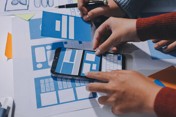 UX UI designer testing prototype on a phone, discussing and brainstorming on wireframes for a...