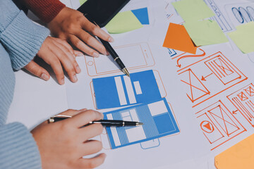 UX UI designer testing prototype on a phone, discussing and brainstorming on wireframes for a...