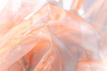 Close-Up of Light Orange Semi-Transparent Fabric with Flowing Texture – Soft, Ethereal Textile...