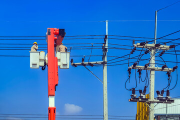 Electricians or engineer on bucket boom truck work to install electrical system on power pole with...