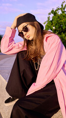 Urban wear. Youthful dancer in trendy attire poised on concrete structure outdoors. Concept of...