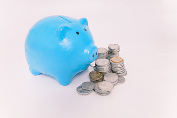Financial Savings. Blue piggy bank and stack of coins isolated on white background. Investment...