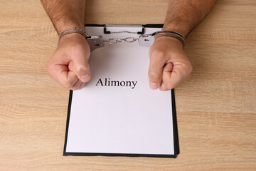 A man in handcuffs holds a document with the inscription 