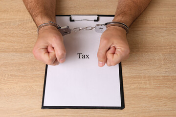 A man in handcuffs holds a document with the inscription 