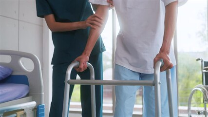 Beautiful asian woman physiotherapist assists Asian man patient in walking exercises using crutches in physical therapy clinic. - Powered by Adobe