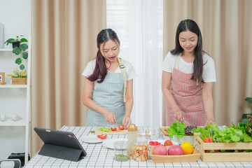 Asian young two women cooking salad in kitchen. Active beautiful girl feel happy and enjoy eating vegetables healthy foods to diet and lose weight for health care in house	