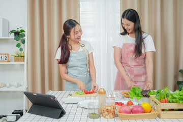 Asian young two women cooking salad in kitchen. Active beautiful girl feel happy and enjoy eating vegetables healthy foods to diet and lose weight for health care in house	