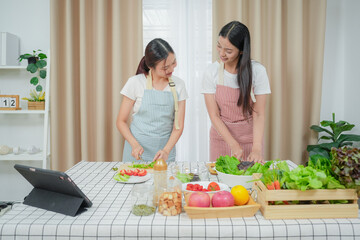 Asian young two women cooking salad in kitchen. Active beautiful girl feel happy and enjoy eating vegetables healthy foods to diet and lose weight for health care in house	