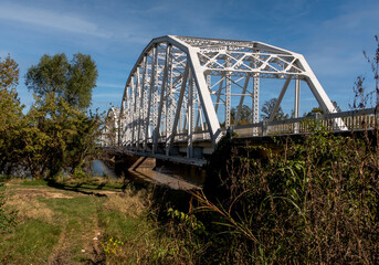 old bridge over the river under a partly cloudy sky next to trees