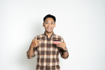 A cheerful young man proudly holding up and pointing to a credit card, symbolizing financial confidence, payment security, and personal identification in modern-day transactions.