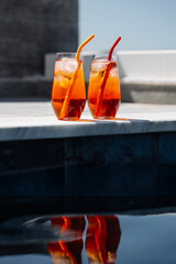 Close up minimalistic  photo of two homemade Aperol spritz cocktails with ice and colorful silicone...