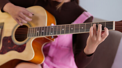 Young Asian woman playing acoustic guitar at home for relaxing and enjoy music hobby