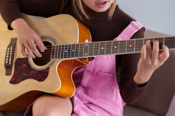 Young Asian women playing guitar creating music and song with her acoustic guitar for entertainment, hobby and art concept