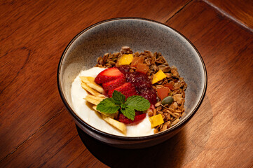 A bowl of yogurt parfait topped with granola, fresh fruit, and jam.