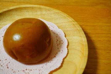 木の皿の上に置かれた白いレースペーパーに載っている、つやつやとした茶色い和菓子が魅力的に写し出された一枚