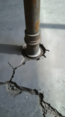 Rusty vertical pipe protruding through cracked concrete slab illustrating rough-in plumbing repair challenge