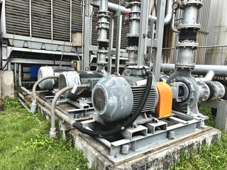 Industrial electric motor pumps installed outdoors with connected pipelines and valves, used in cooling systems, HVAC, and fluid transfer operations in factories or energy plants.