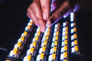 Close-up of a person cleaning yellow mechanical keyboard switches using a cotton bud. Illuminated keys create a modern tech vibe. Ideal for maintenance, modding, or keyboard tutorial content.