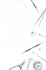 Stomatological tools on dentist's desk on white background top-down frame copy space