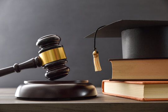 Educational trial with gavel, books, and mortarboard isolated on black