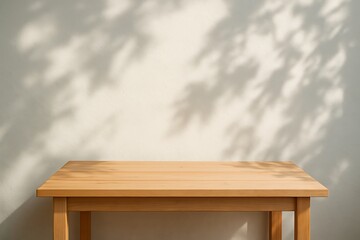 A light wooden table sits against a wall with leaf shadows