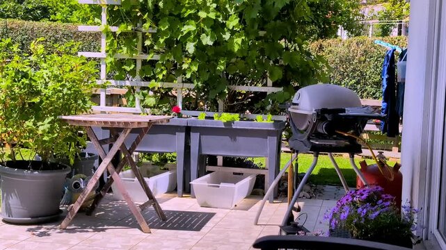 Garden Terrace with Grill and Plants on a Sunny Spirng Day.