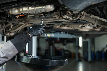 Worker removing dirty old motor oil from car engine, closeup