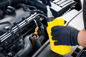 Worker checking motor oil level in car with dipstick, closeup
