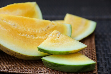 Pieces of ripe yellow watermelon on wicker table, closeup