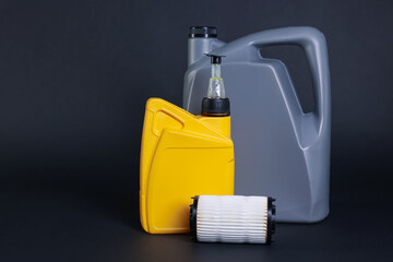 Motor oil in plastic canisters and filter on dark grey background, space for text