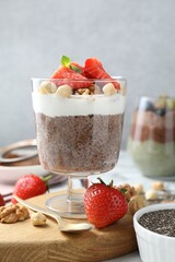 Delicious chocolate pudding with chia seeds, strawberries, yogurt and nuts in glass on table, closeup