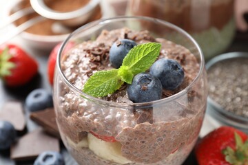 Delicious chocolate pudding with chia seeds and blueberries in glass on table, closeup